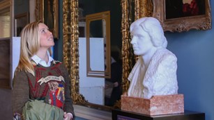 Visitor looking at busts and paintings of suffragists