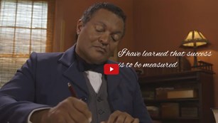 Screenshot from a film showing a reenactment of Booker T. Washington writing