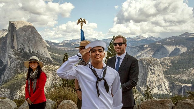 Sailor saluting with scenic mountain range in the background