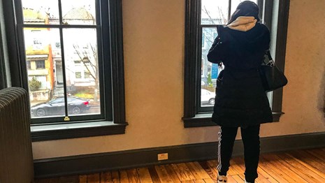 Visitor looking out a window at a row of townhouses