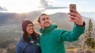 Two visitors taking a selfie in front of a canyon