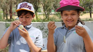 Two kids holding up necklaces