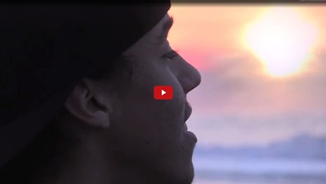 Screenshot from film of a person talking near the ocean