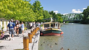 People walking along a canal where a boat is tied