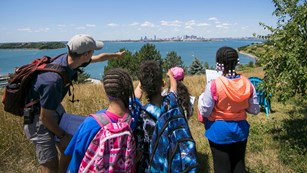 Guide pointing kids to a city skyline across a body of water