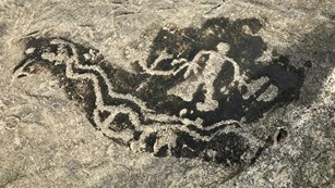 Petroglyph on a rock thta includes a human-like figure
