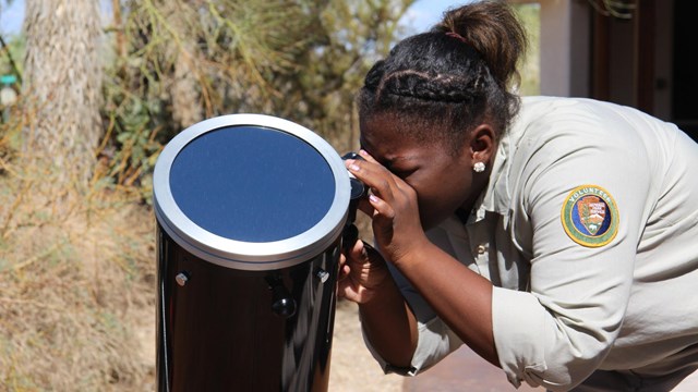 Female volunteer looking through telescope