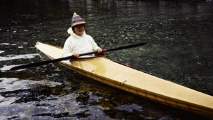 Historical color photo of a woman in a traditional kayak