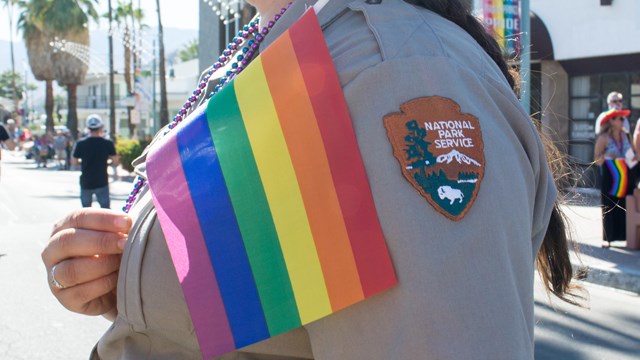 Park Ranger holding a pride flag in a parade