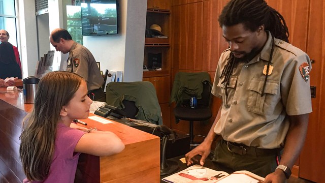 Park ranger going over a Junior Ranger book with a kid