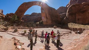Park ranger talking to a group of visitors near a geological arch