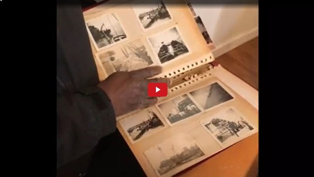 Screenshot from a video showing a person holding a scrapbook with historical photos 
