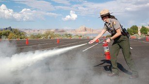 Ranger using a fire extinguisher on a roadway