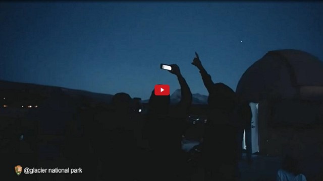 Video screenshot of people looking up at the night sky