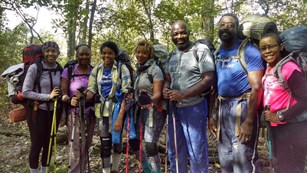 Group of hikers with gear standing in the woods