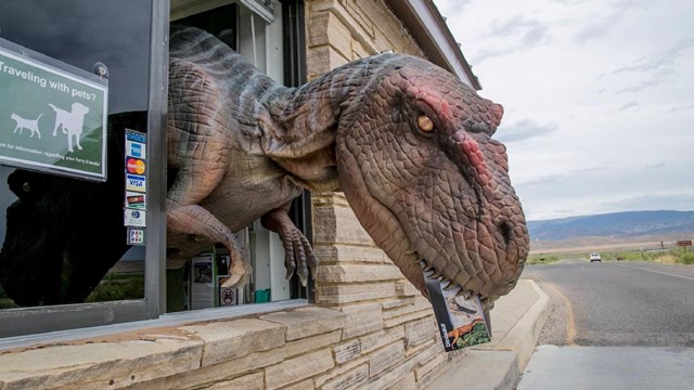 Dinosaur handing out a brochure at an entrance station booth