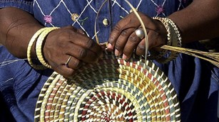 Hands weaving a basket