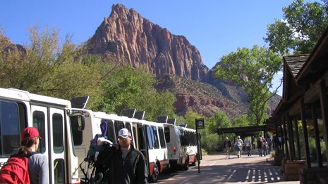 Long shuttle bus at a bus stop at the base of a mountain