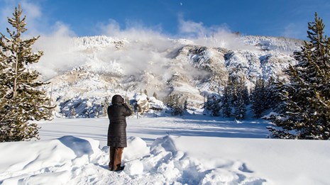 Person on foot photographing a mountain in the snow