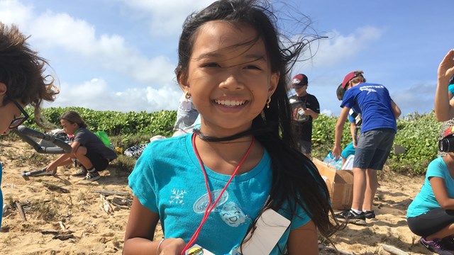 Child on a beach holding a park pass