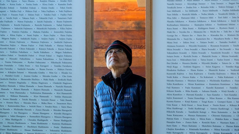 Person standing between two walls with many names listed on each