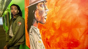 Park Ranger Elijah Prince standing next to his painting of a ranger