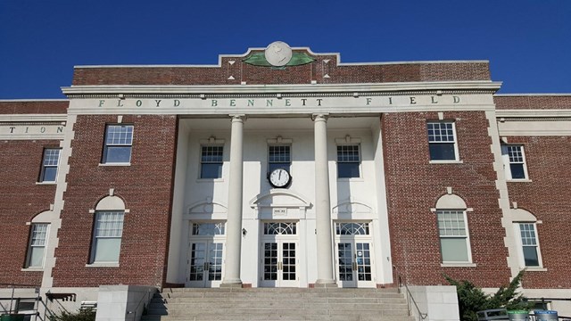 Large two-story brick building with letting reading "Floyd Bennett Field" over the entrance