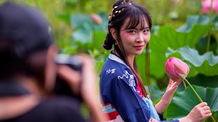 Photographer taking a picture of a woman in traditional Japanese attire holding a flower