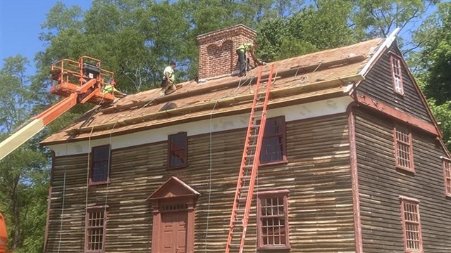 9 people in front of a historic wood barn.