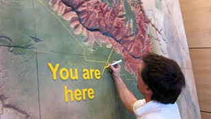 Person installing a wall map of the Grand Canyon