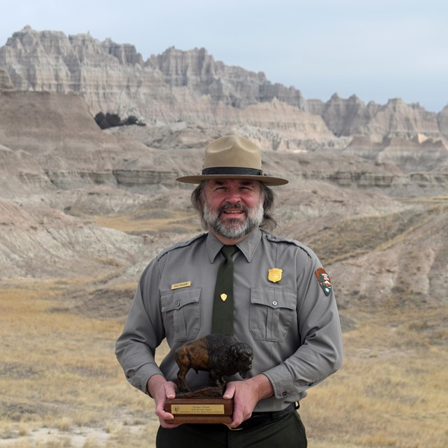 Ranger holding an award near a canyon