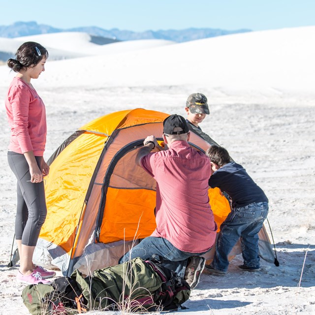 Family putting up a tent in a white sand desert
