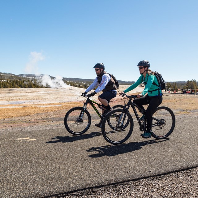 Bicyclist on a road near a geyser