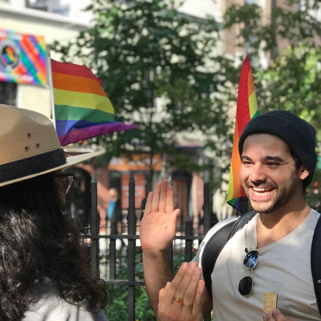 Visitor taking a Junior Ranger pledge with a ranger near Pride flags