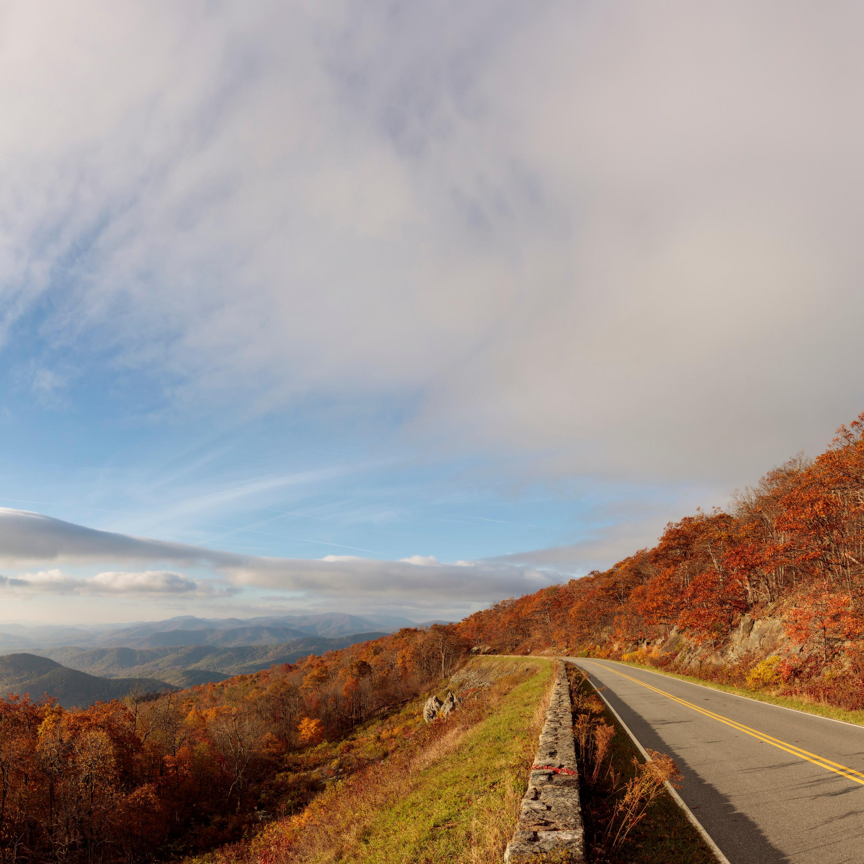 Mountain road lined with fall foliage and views of the valley