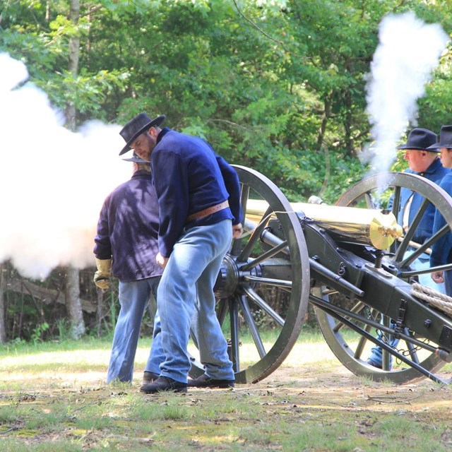 people firing an old cannon during a demonstration