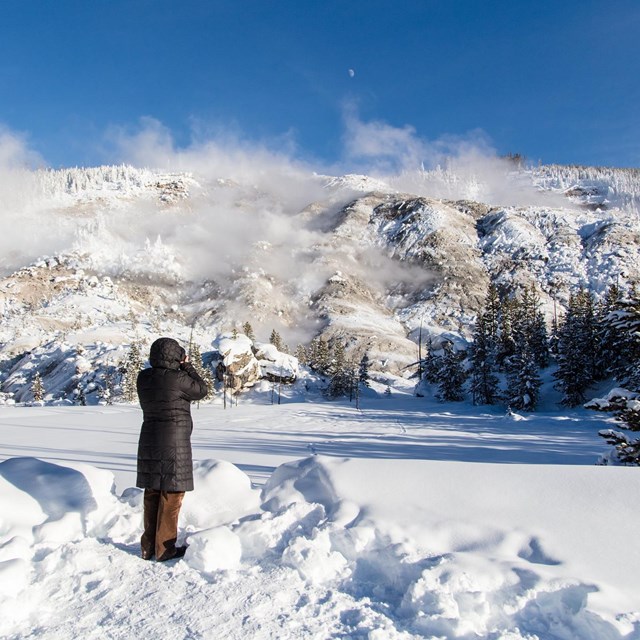 Person on foot photographing a mountain in the snow