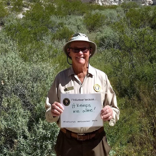 Volunteer holding up a sign saying why they volunteer