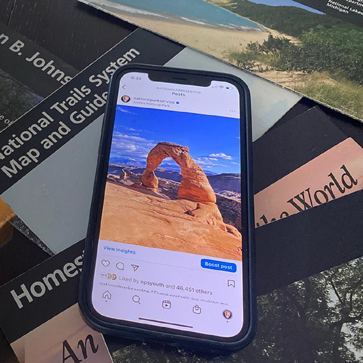 Smartphone displaying a social media post on top of the National Park Service logo