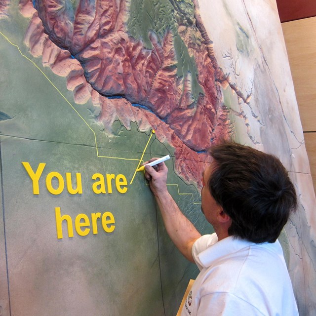 Person installing a wall map of the Grand Canyon