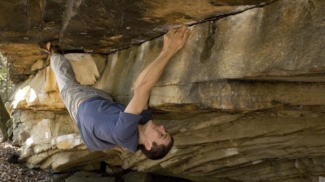 A young man hanging upside down climbing.