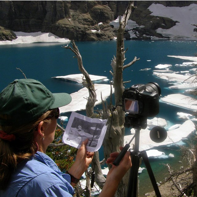 woman with camera looking over a river with melting snow