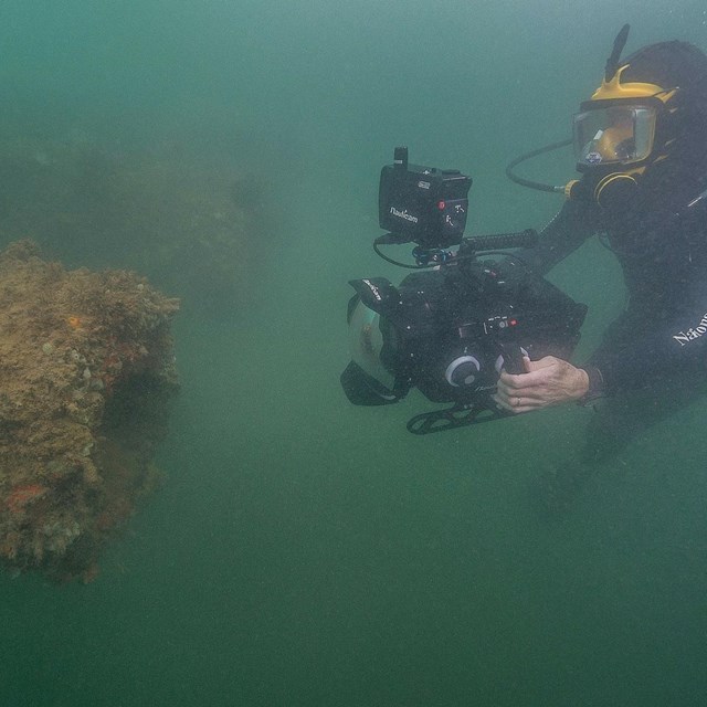 scuba diver filming shipwreck underwater