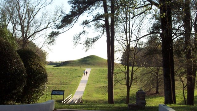 People walk up the path to the earth lodge.