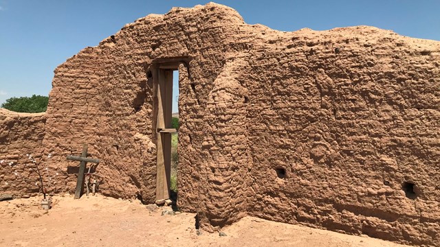 A weathered adobe wall with a cut out door.