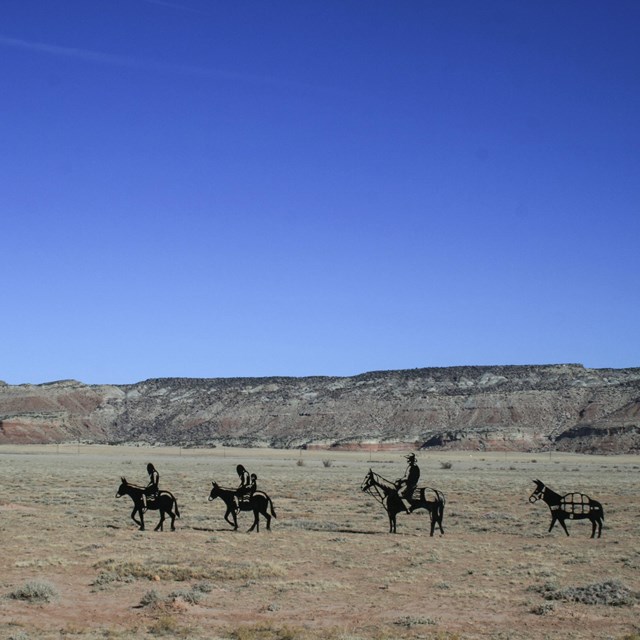 A weathered adobe building sits in a desert landscape.