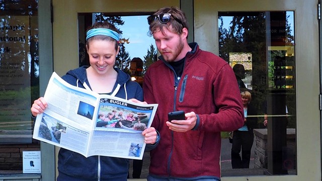 Visitors look over Olympic National Park newspaper The Buglar.