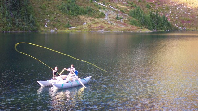 Fishing off of a small boat on a lake.