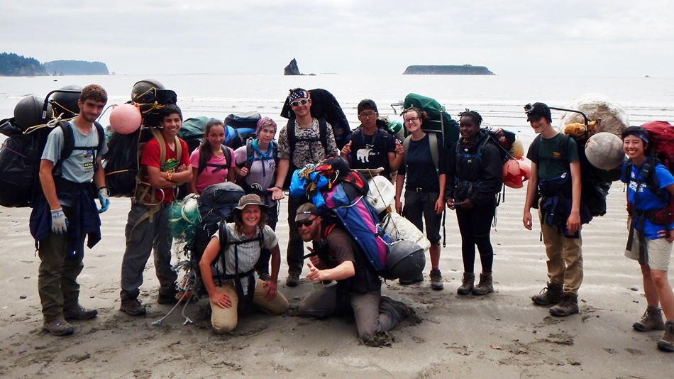 High school volunteers group photo with backpacks and marine debris