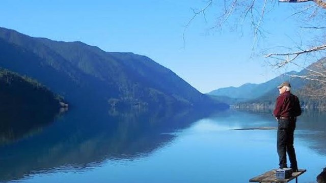 A man stands on a nearly-submerged picnic table at Lake Crescent.